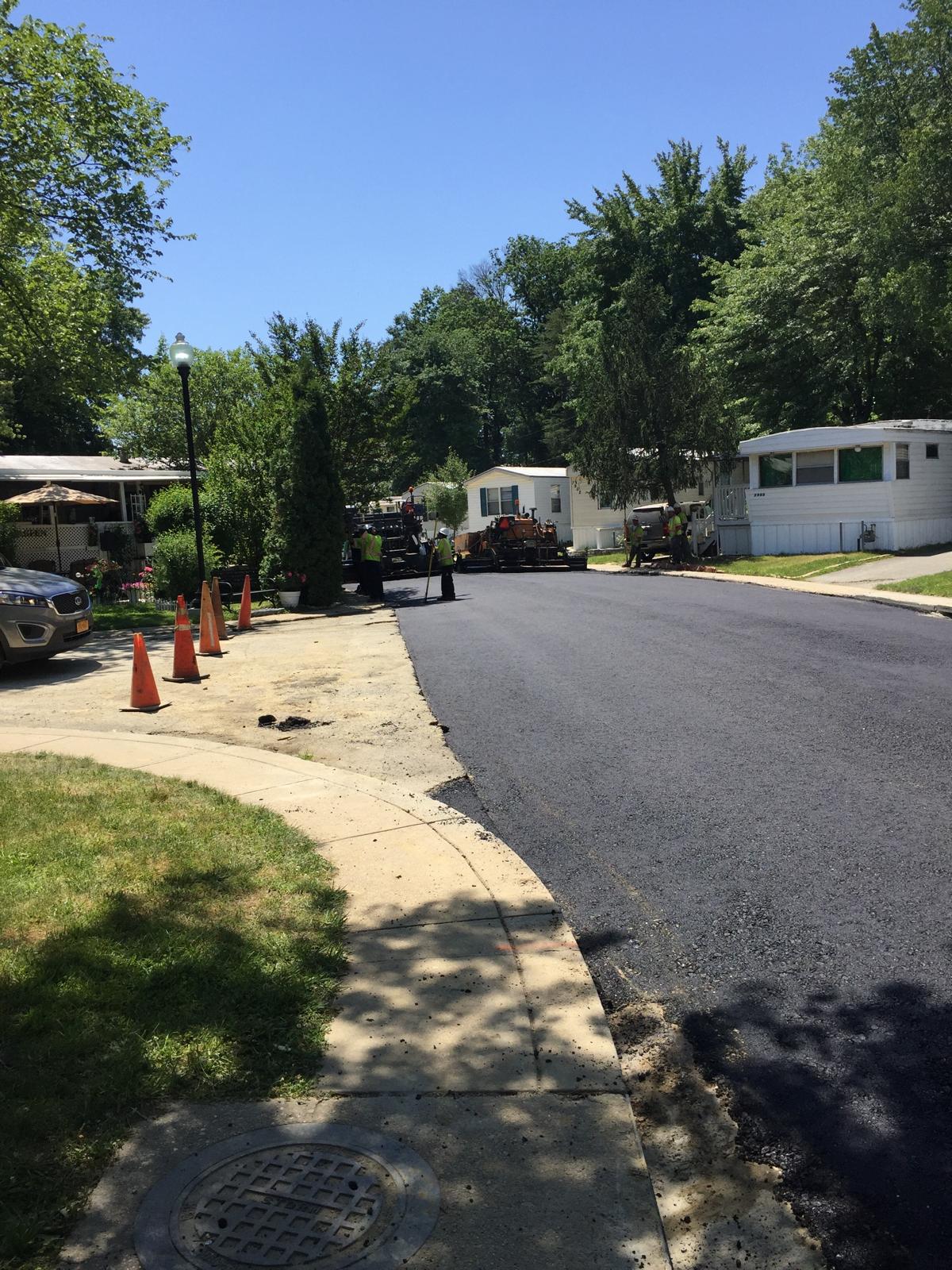 Route traitée LL-TEQ en service au cœur d'un quartier arboré — surface scellée, ruissellement propre.
