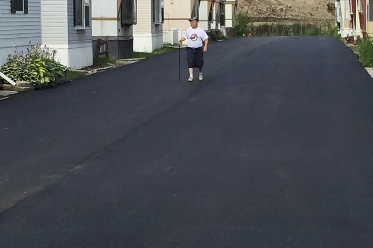 A community resident walking on a finished LL-TEQ residential street — open to everyday traffic in hours, not weeks