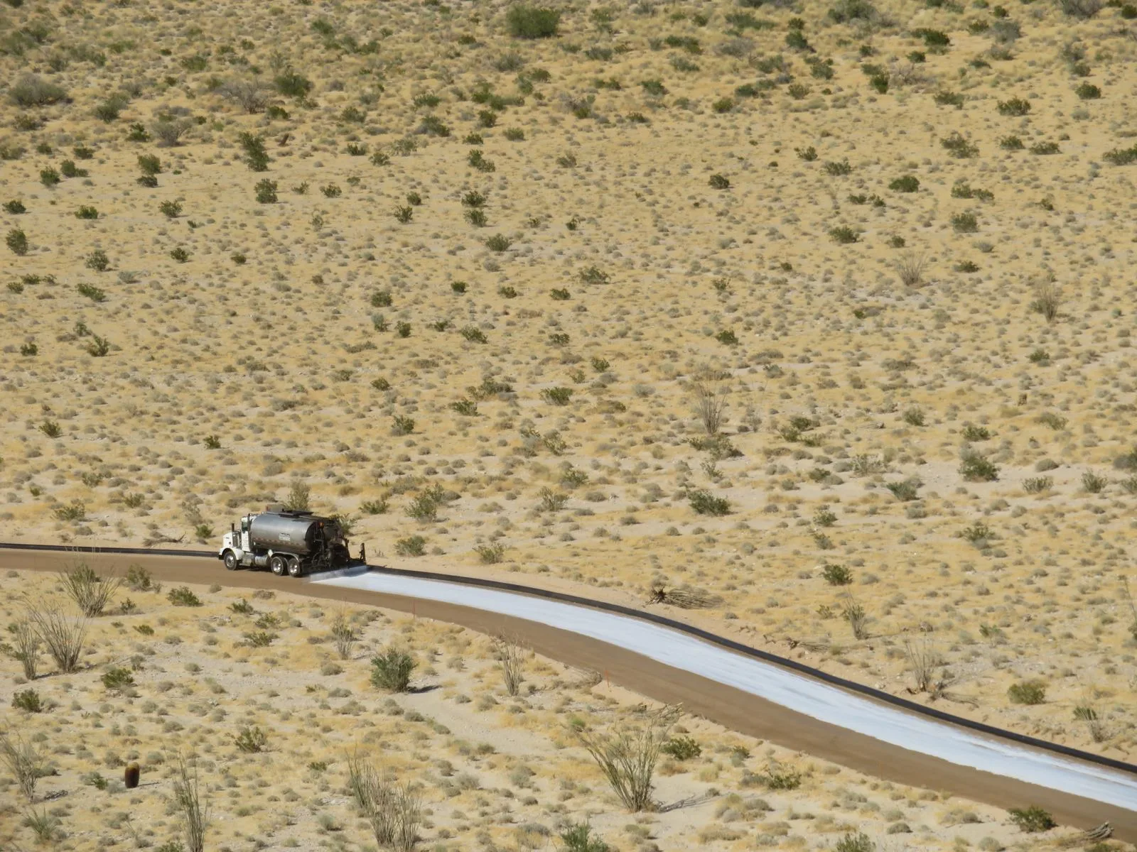 Water truck applying the topical LL-TEQ seal after compaction