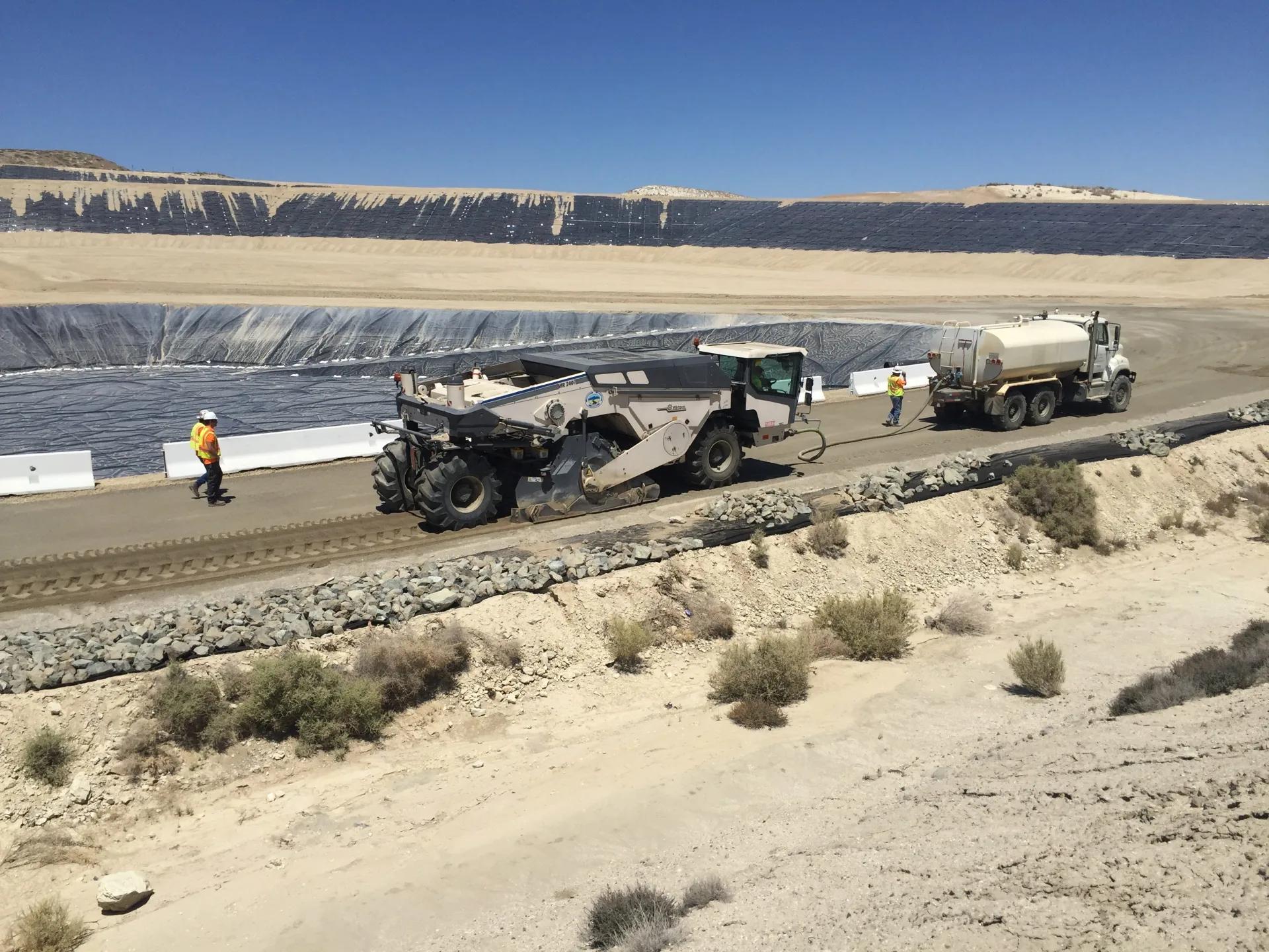 LL-TEQ reclaimer and tanker truck treating road in arid terrain
