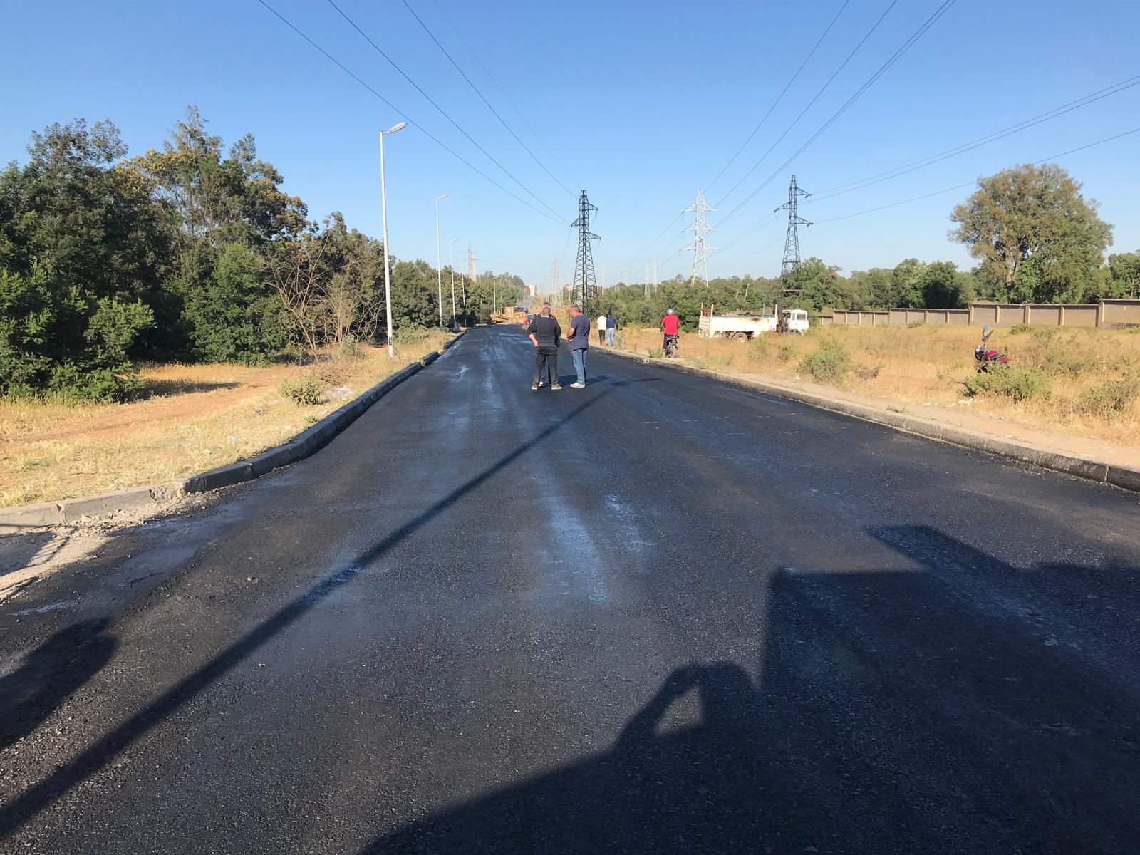 Route publique fraîchement réhabilitée traversant un secteur habité
